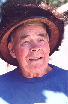 Norm Bourgeois in his later years wearing a blue T-shirt and brown furry hat.
