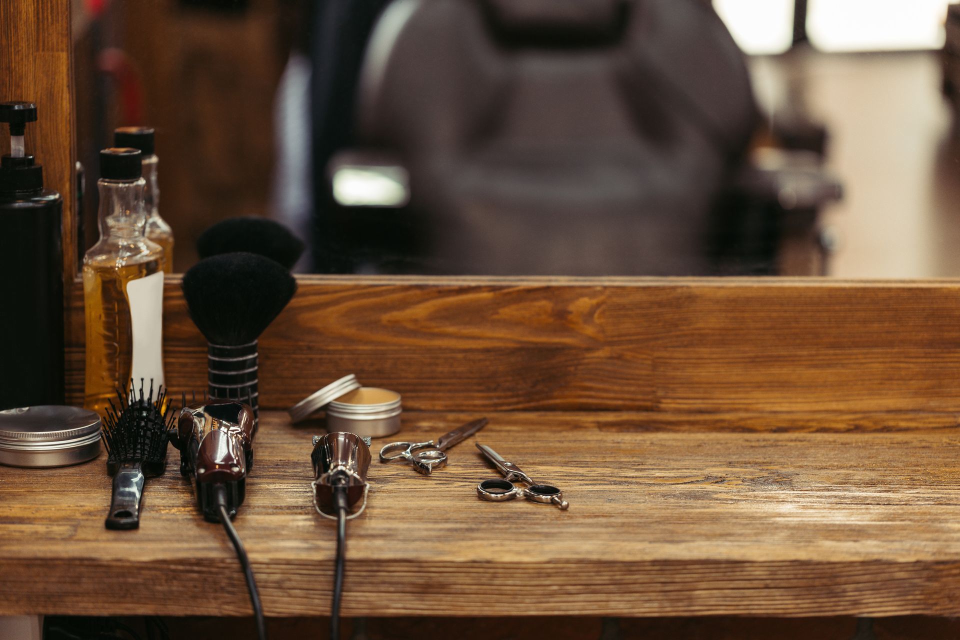 Barber shop tools on a wooden shelf, including clippers, brushes, scissors, and bottles.