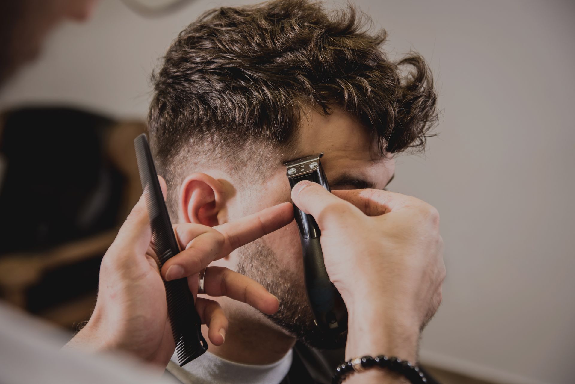 Barber using clippers to trim a client's hairline at a salon.