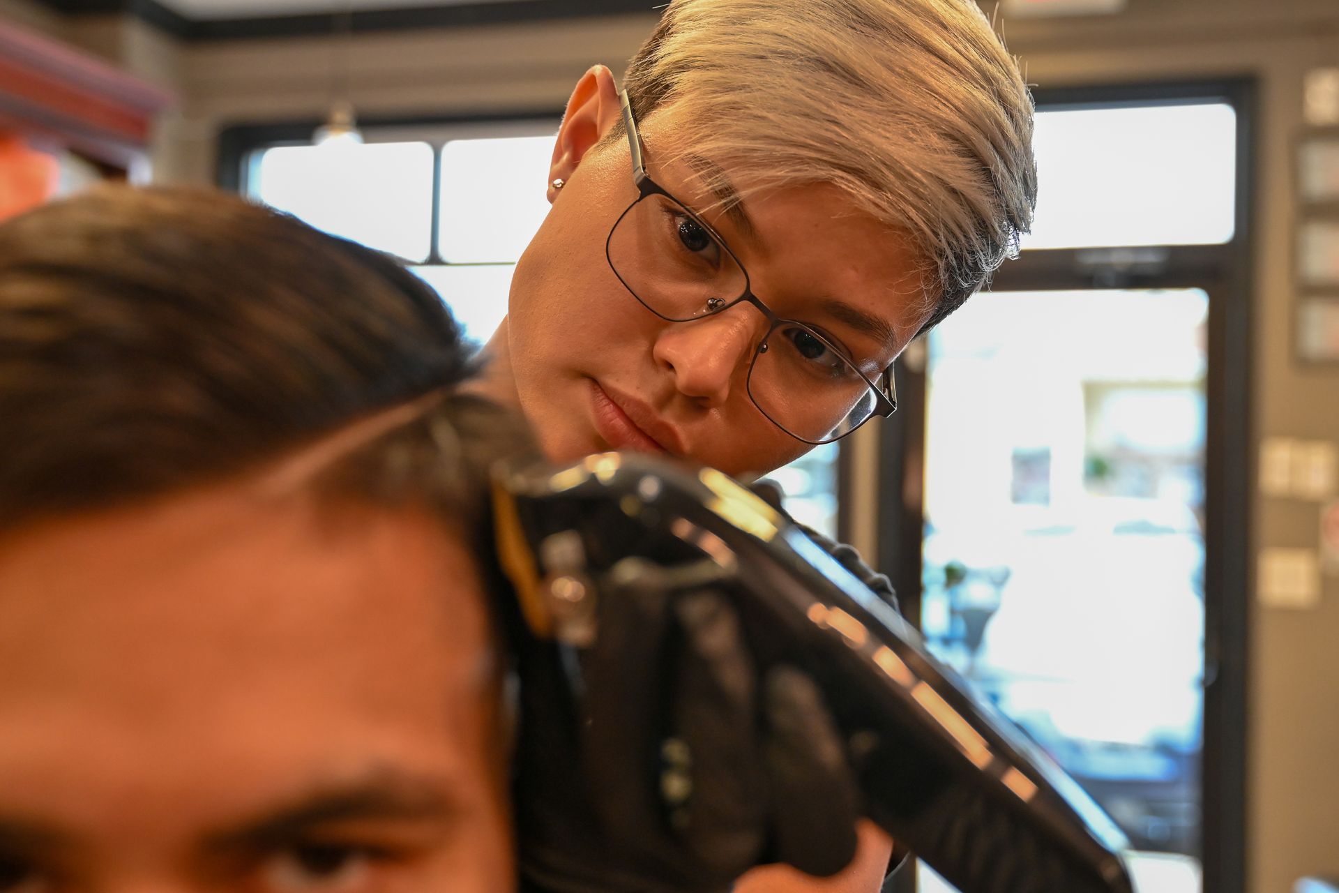 A woman is cutting a man 's hair in a barber shop.