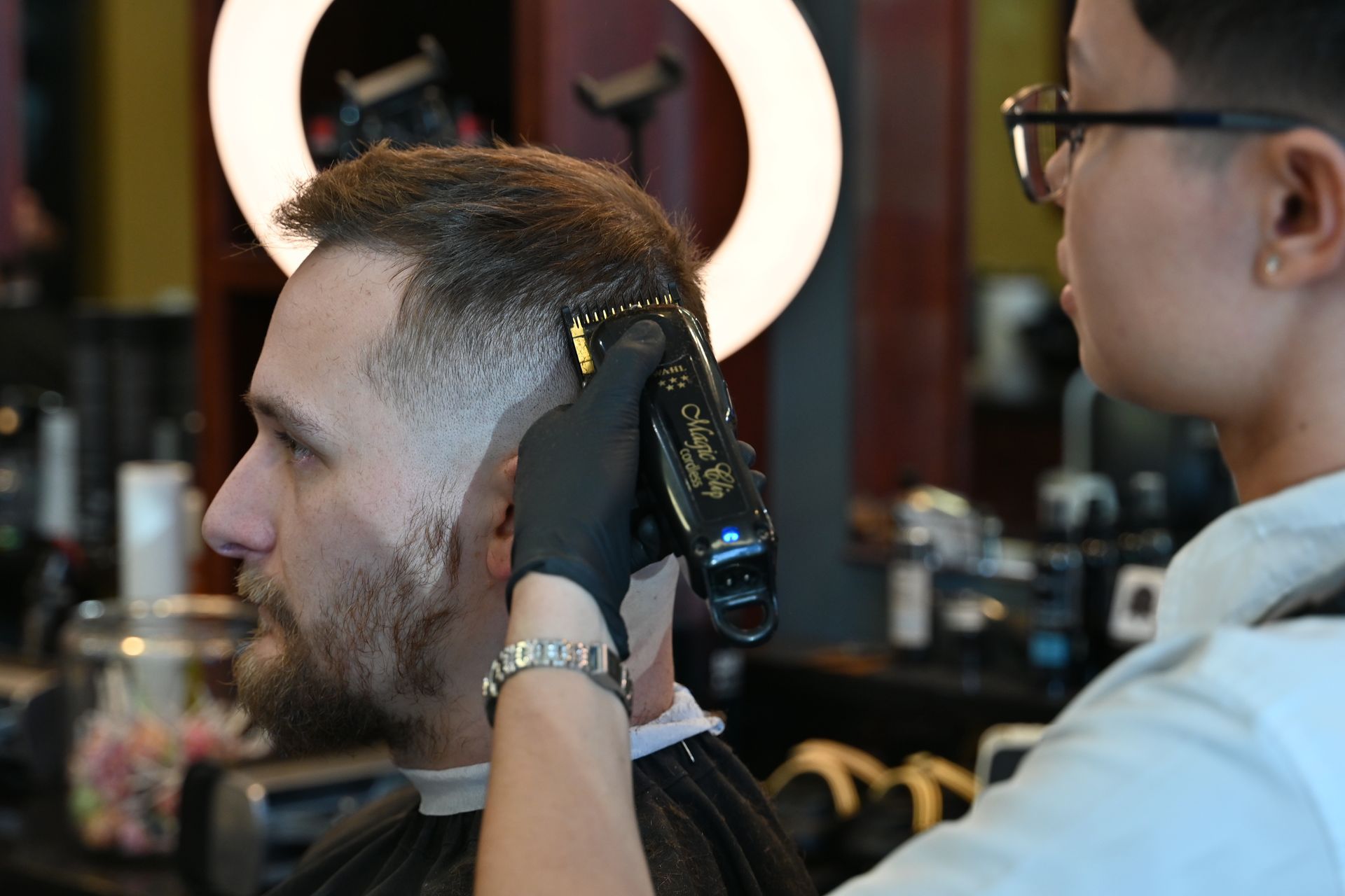 A man is getting his hair cut by a barber in a barber shop.