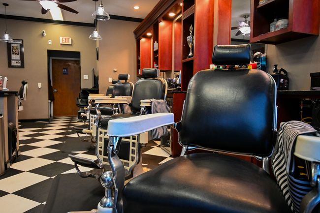 A barber shop with a row of chairs and a checkered floor.