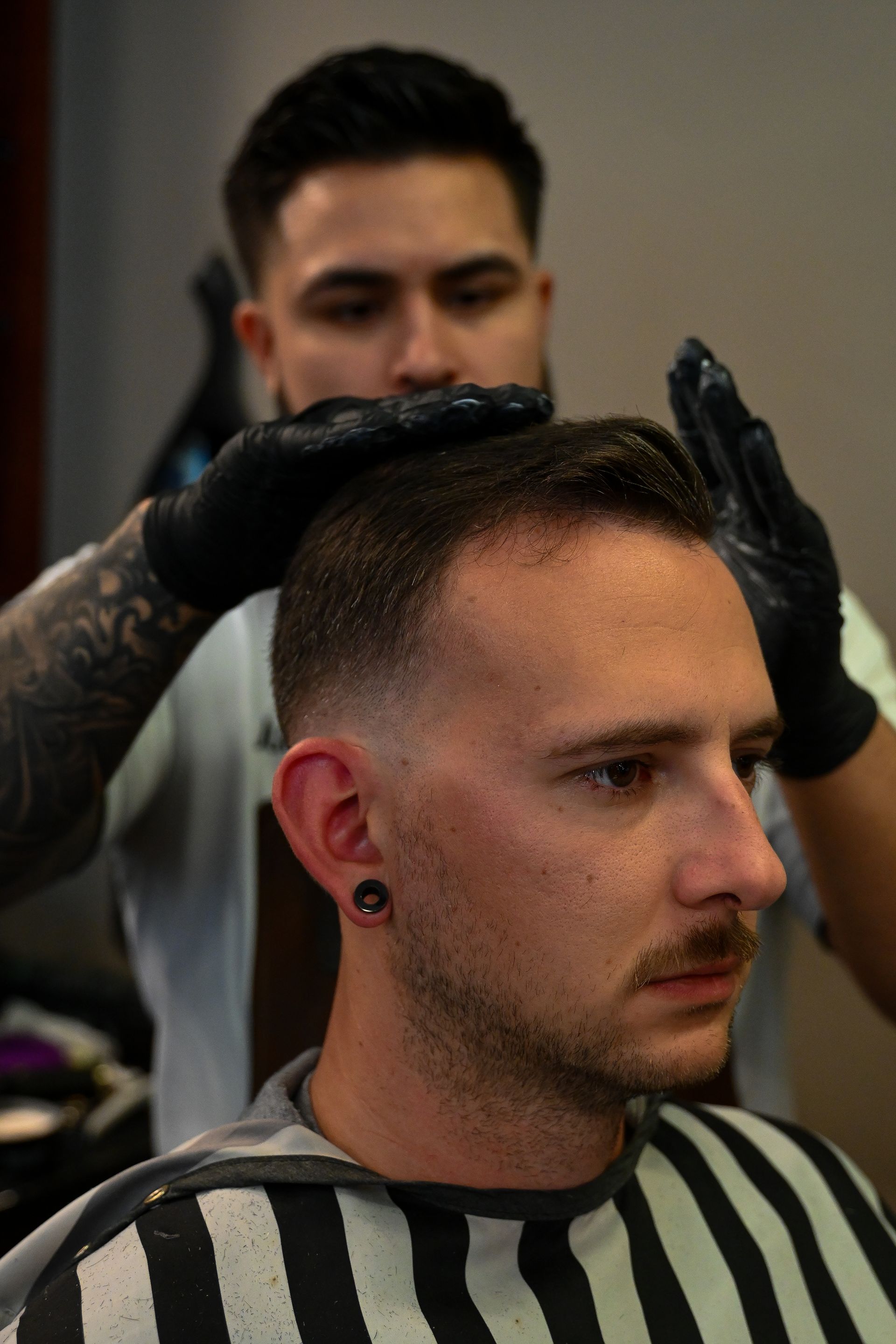 A man is getting his hair cut by a barber in a barber shop.