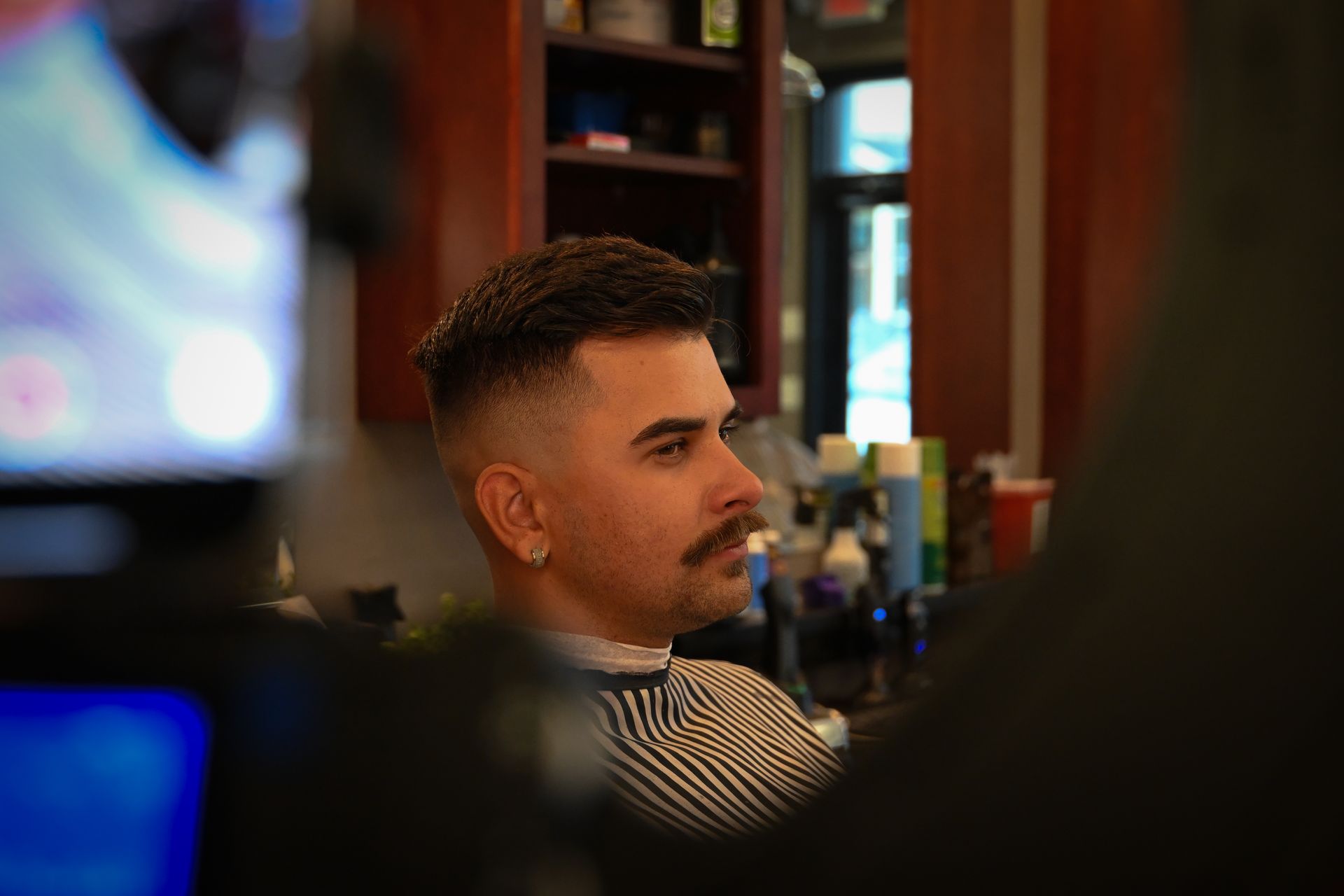 A man is getting his hair cut at a barber shop.