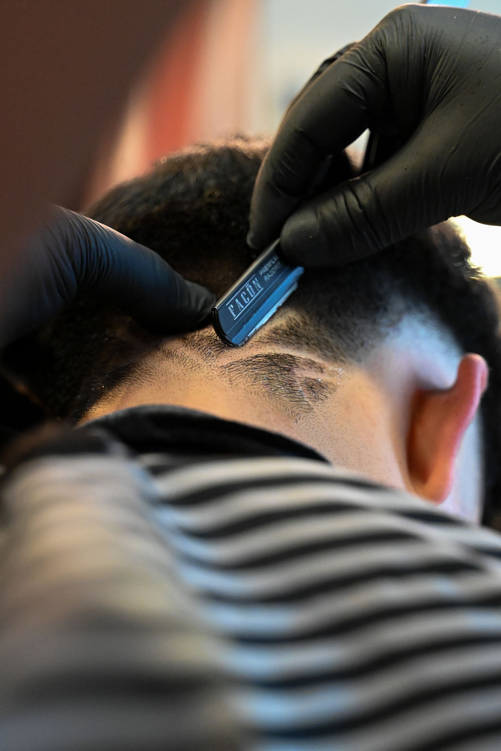 A man is getting his hair cut by a barber wearing black gloves.