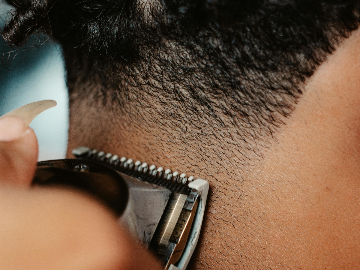 Barber using clippers to trim the back of a person's neck; close up.