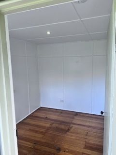 Empty white-walled room with wooden floor, viewed from doorway.