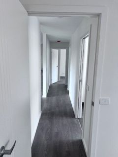 Hallway with gray flooring, white walls, and doorways leading to other rooms.