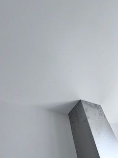 White ceiling with a gray pillar in a corner.