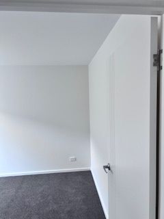 White room with dark gray carpet, a white door slightly open.