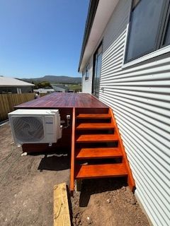 Wooden deck and stairs leading up to house with air conditioning unit.