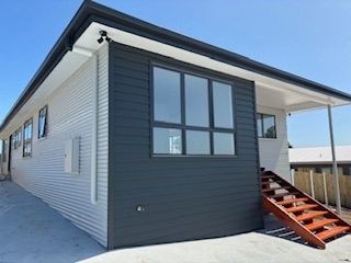 Modern house with gray and white siding, stairs, and large windows.