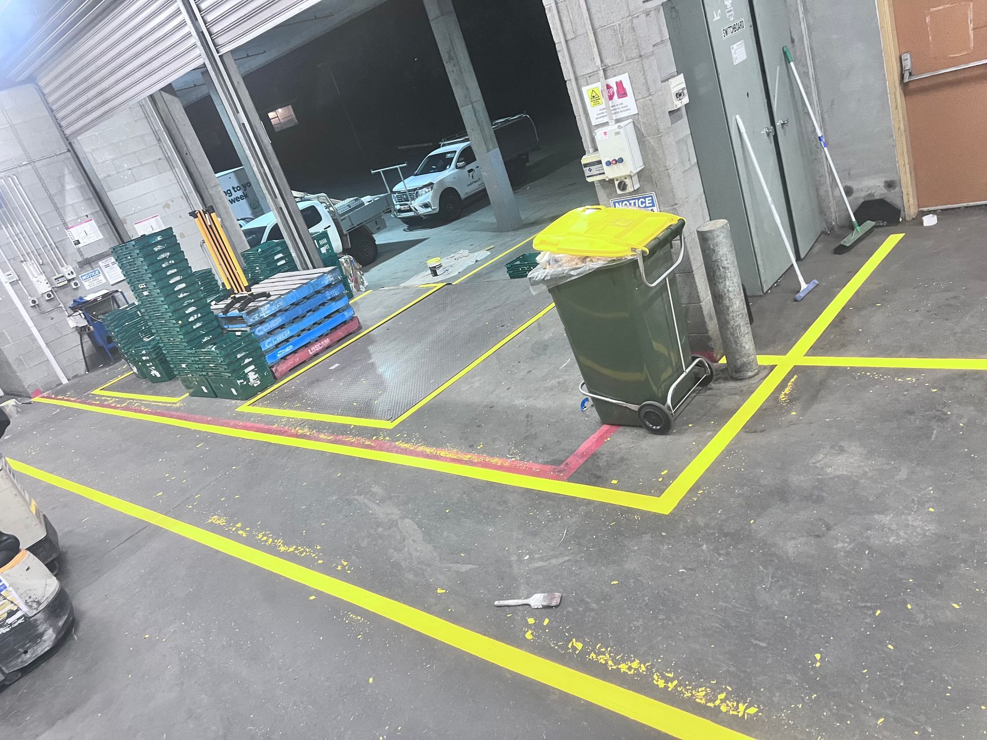 A warehouse with yellow lines on the floor and a green trash can — Hobart, TAS — Campbell Painters Pty Ltd