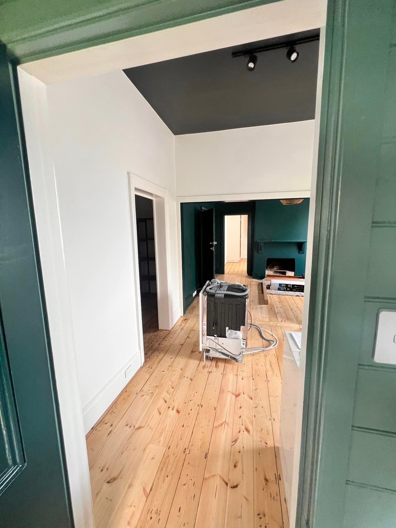View through doorway of a renovated home with wood floors, green walls, and white trim.