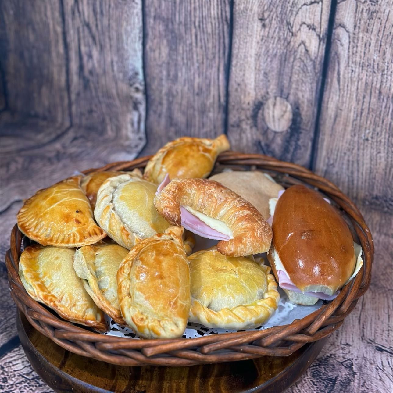 A basket filled with pastries and sandwiches on a wooden table.