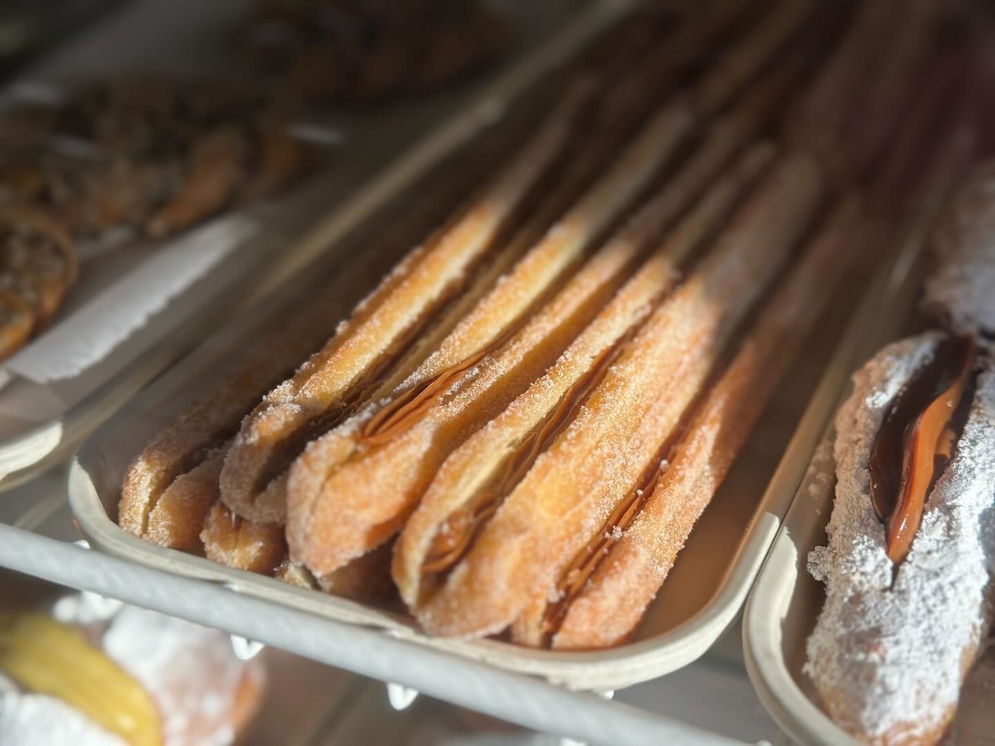 A close up of a tray of churros in a bakery.