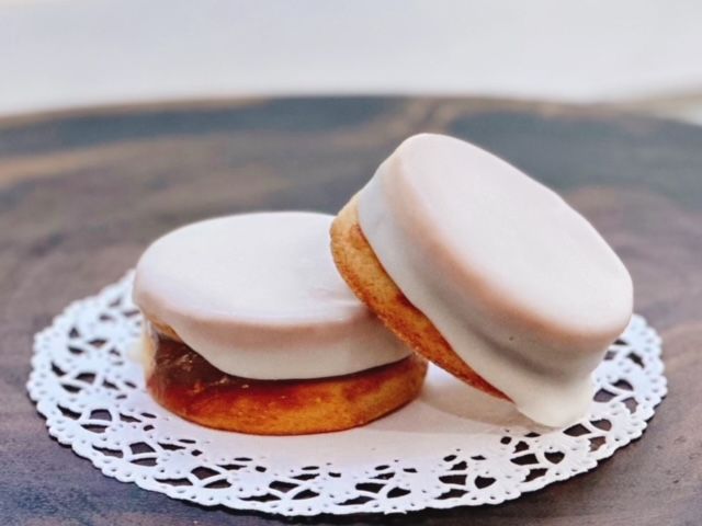 Two cookies with white frosting on a lace napkin