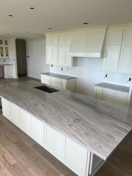 A kitchen with white cabinets and granite counter tops.