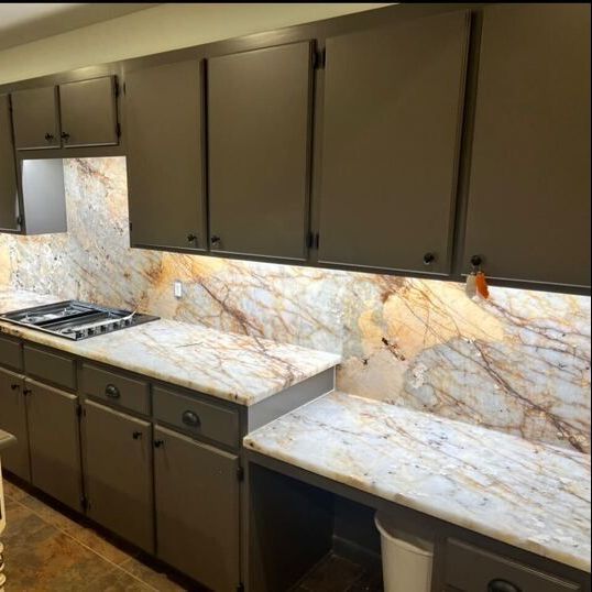 A kitchen with gray cabinets and marble counter tops
