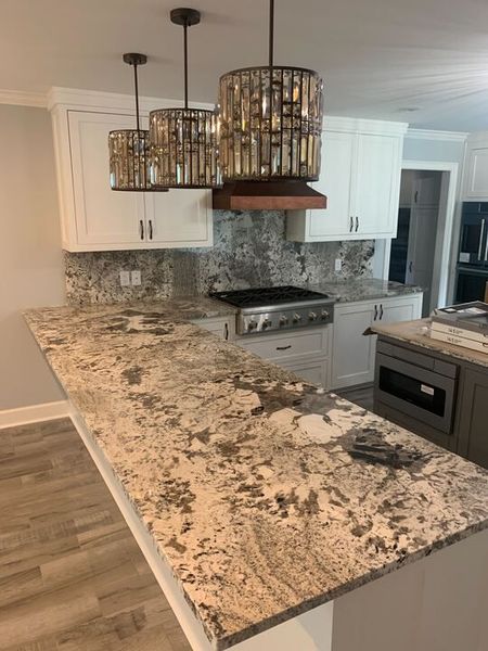 A kitchen with granite counter tops and white cabinets.