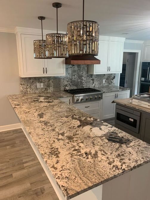 A kitchen with granite counter tops and white cabinets.