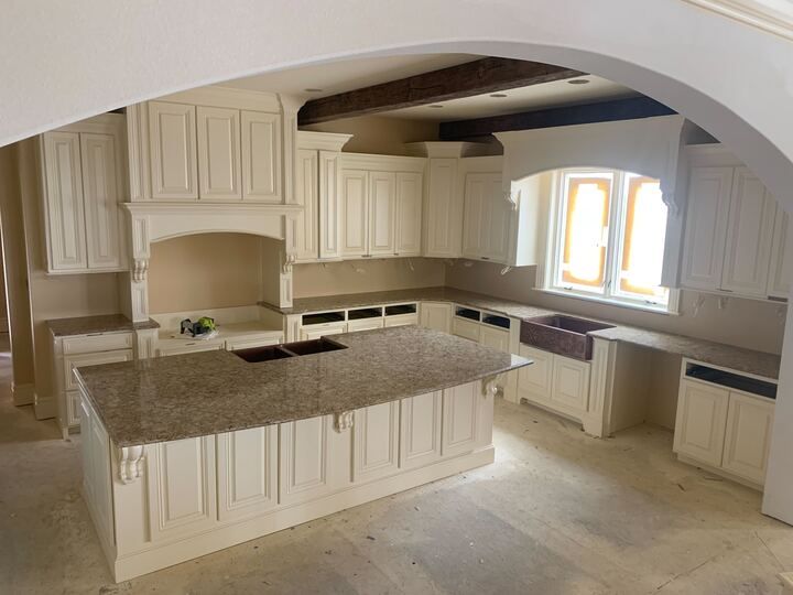 An empty kitchen with white cabinets and granite counter tops
