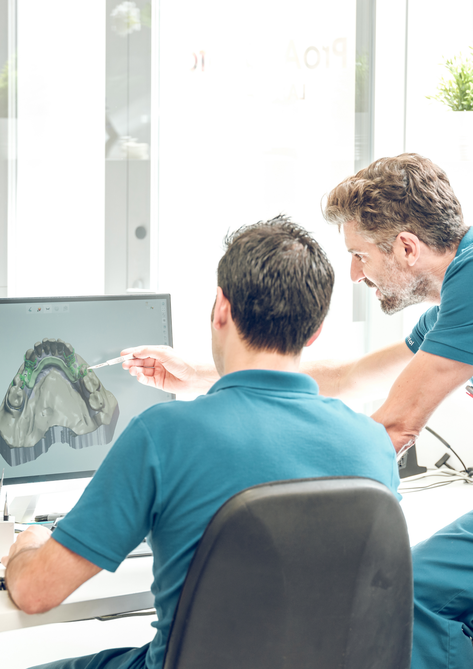 Two men are looking at a computer screen together.