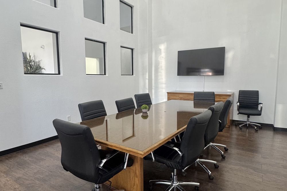 A conference room with a long table and chairs and a flat screen tv.