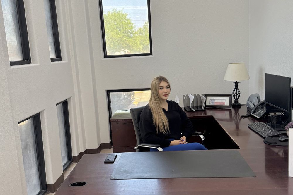 A woman is sitting at a desk in an office.