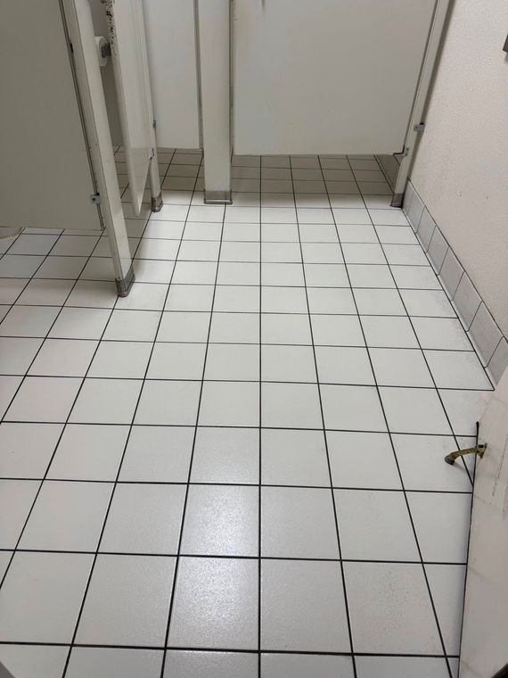 A bathroom with white tiles and black lines on the floor
