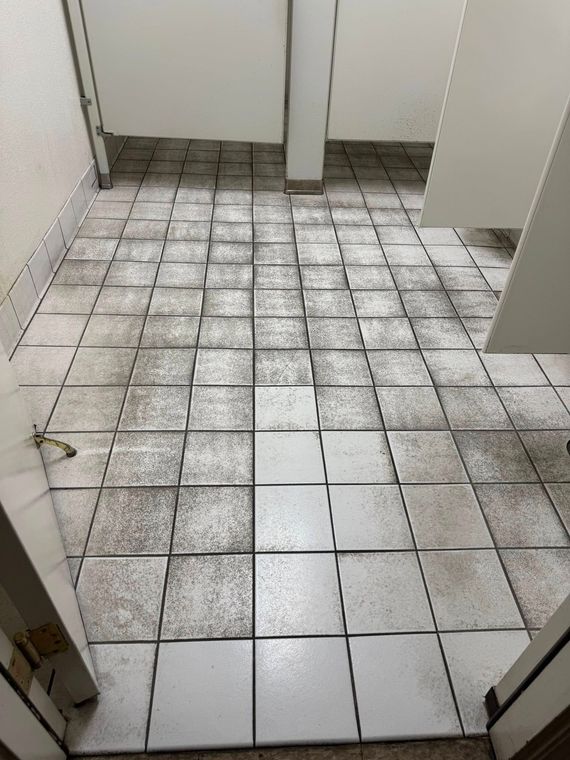 A dirty tiled floor in a public restroom.