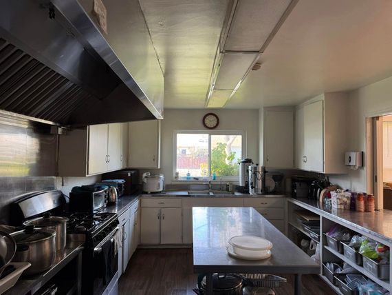 A kitchen with stainless steel appliances and a clock on the wall.