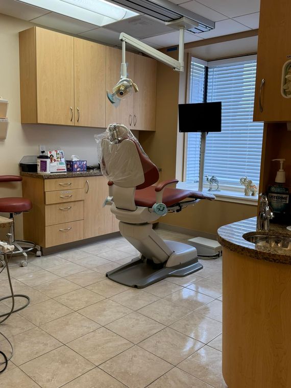 A dental office with a dental chair and a sink.