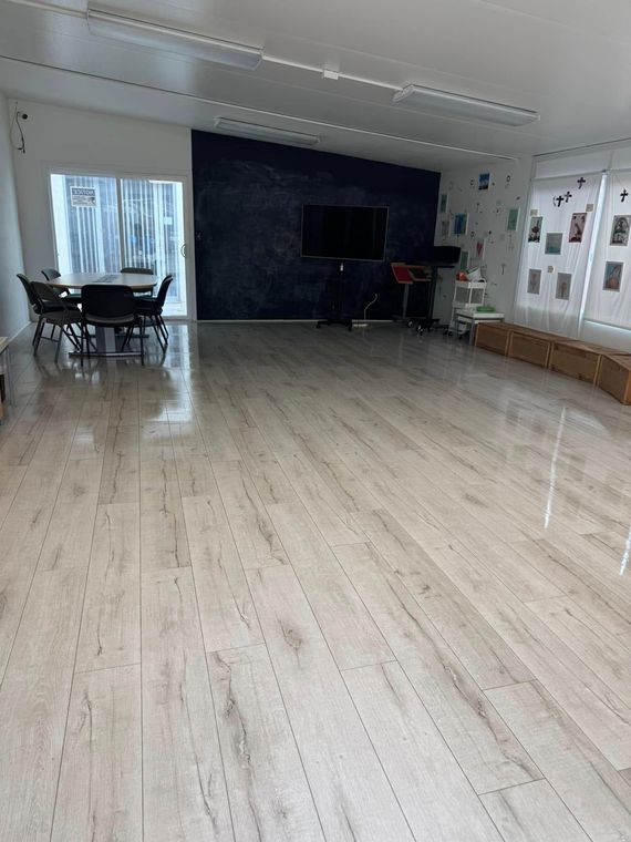 A large room with a wooden floor and a table and chairs.