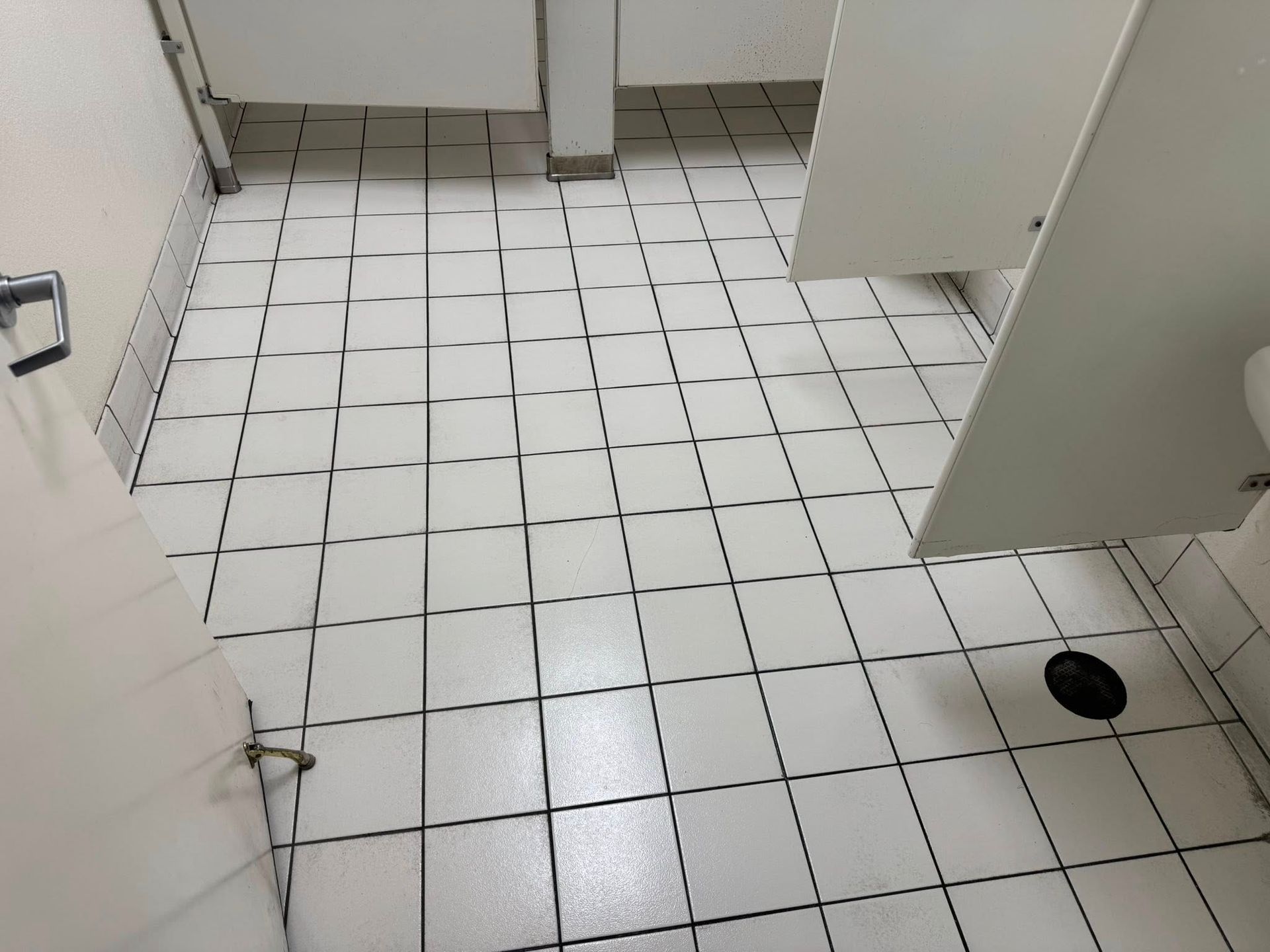 A bathroom with white tiles and a toilet.