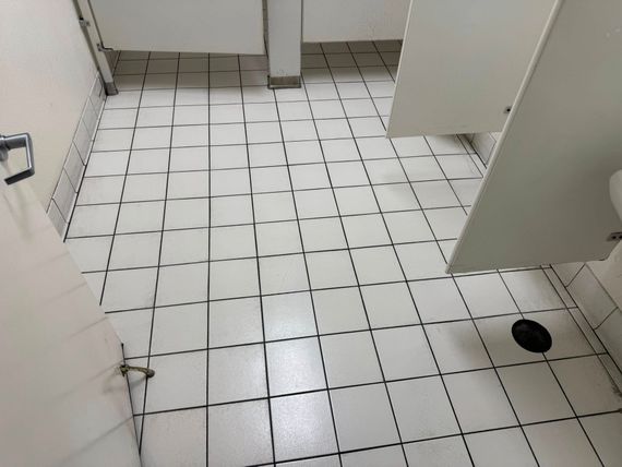 A bathroom with white tiles and a toilet.