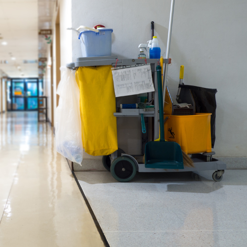 A cleaning cart in a hallway has a sign on it that says welcome