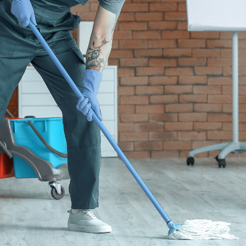A man wearing blue gloves is cleaning the floor with a mop.