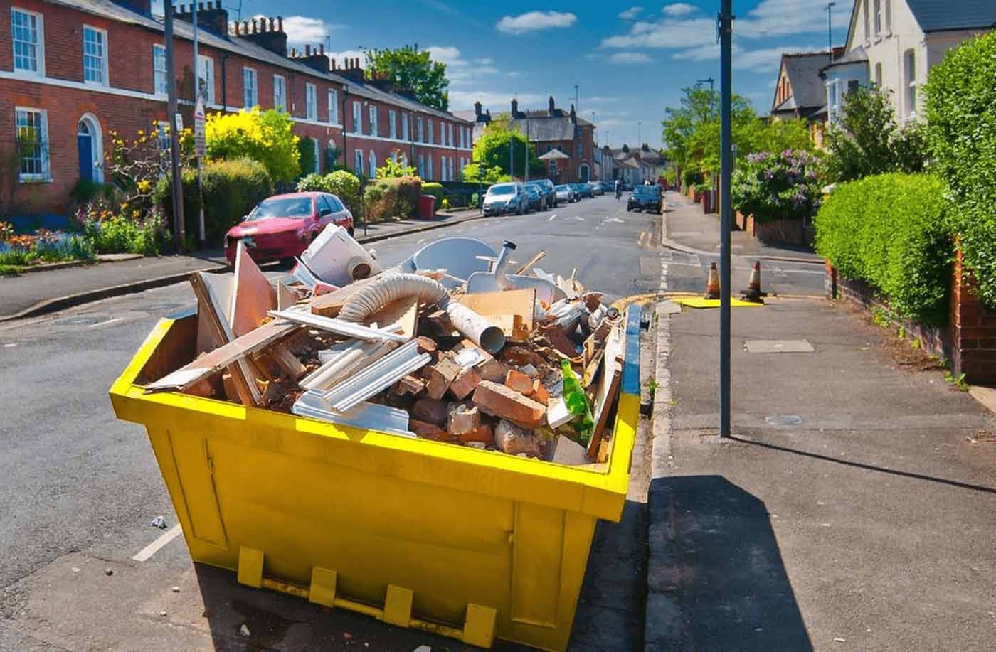 A yellow dumpster filled with trash is parked on the side of the road.