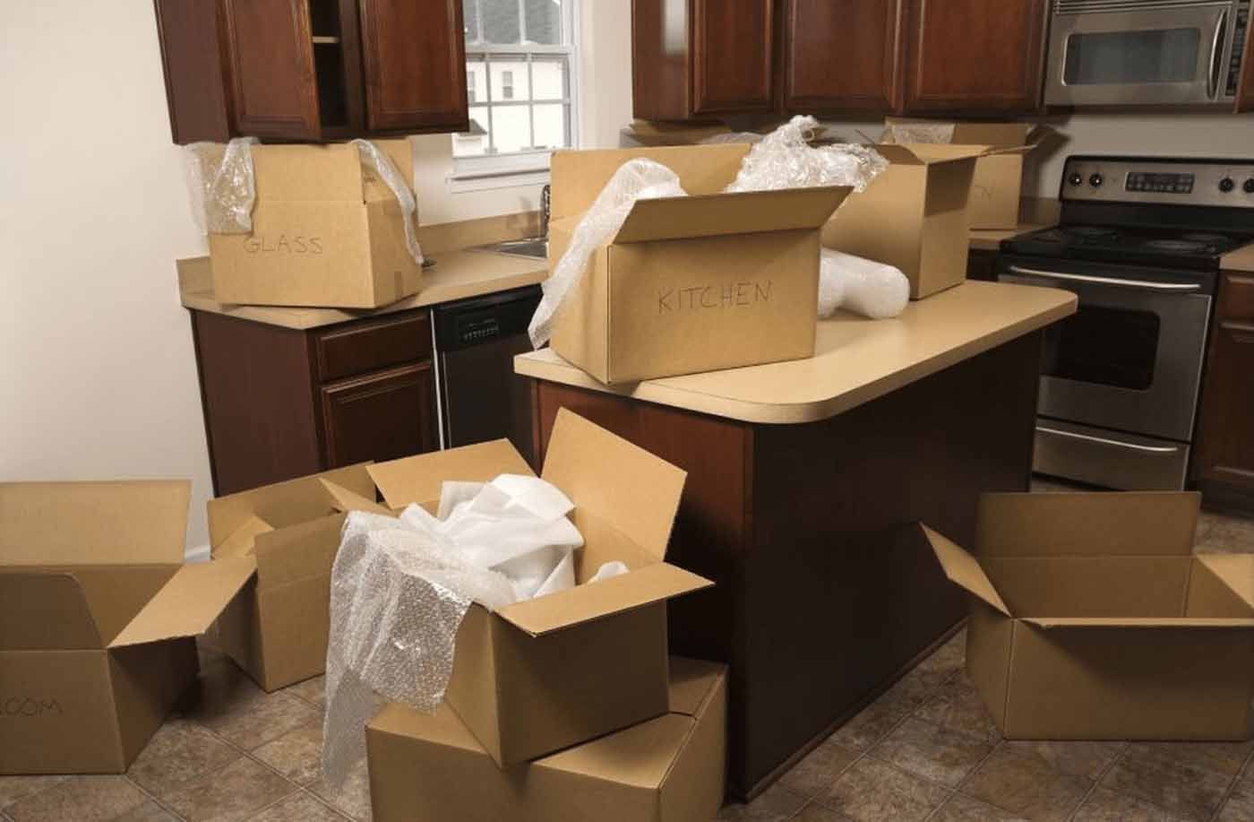 A kitchen with a lot of cardboard boxes on the counter