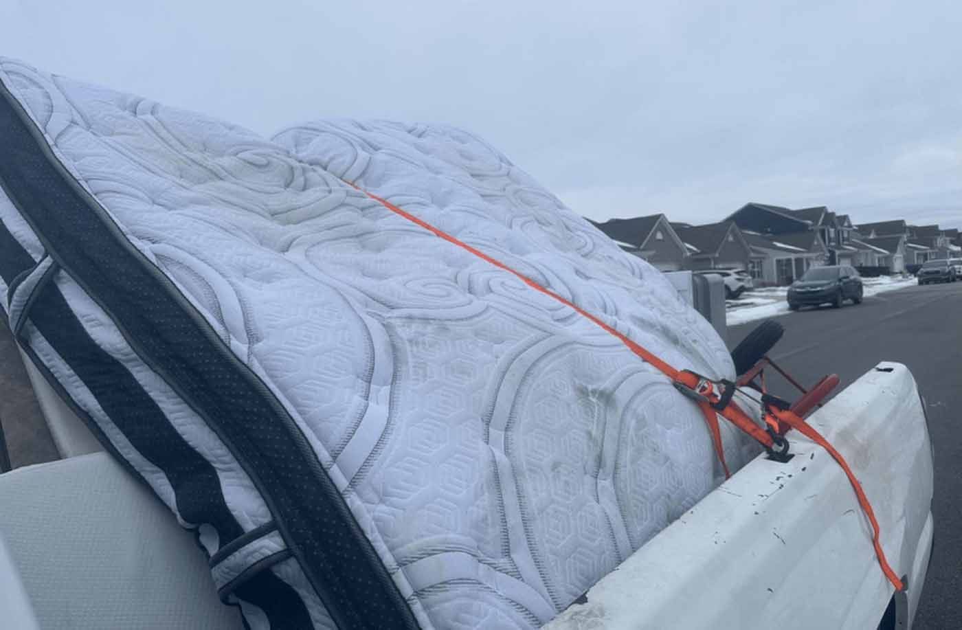 A mattress is tied to the back of a truck.