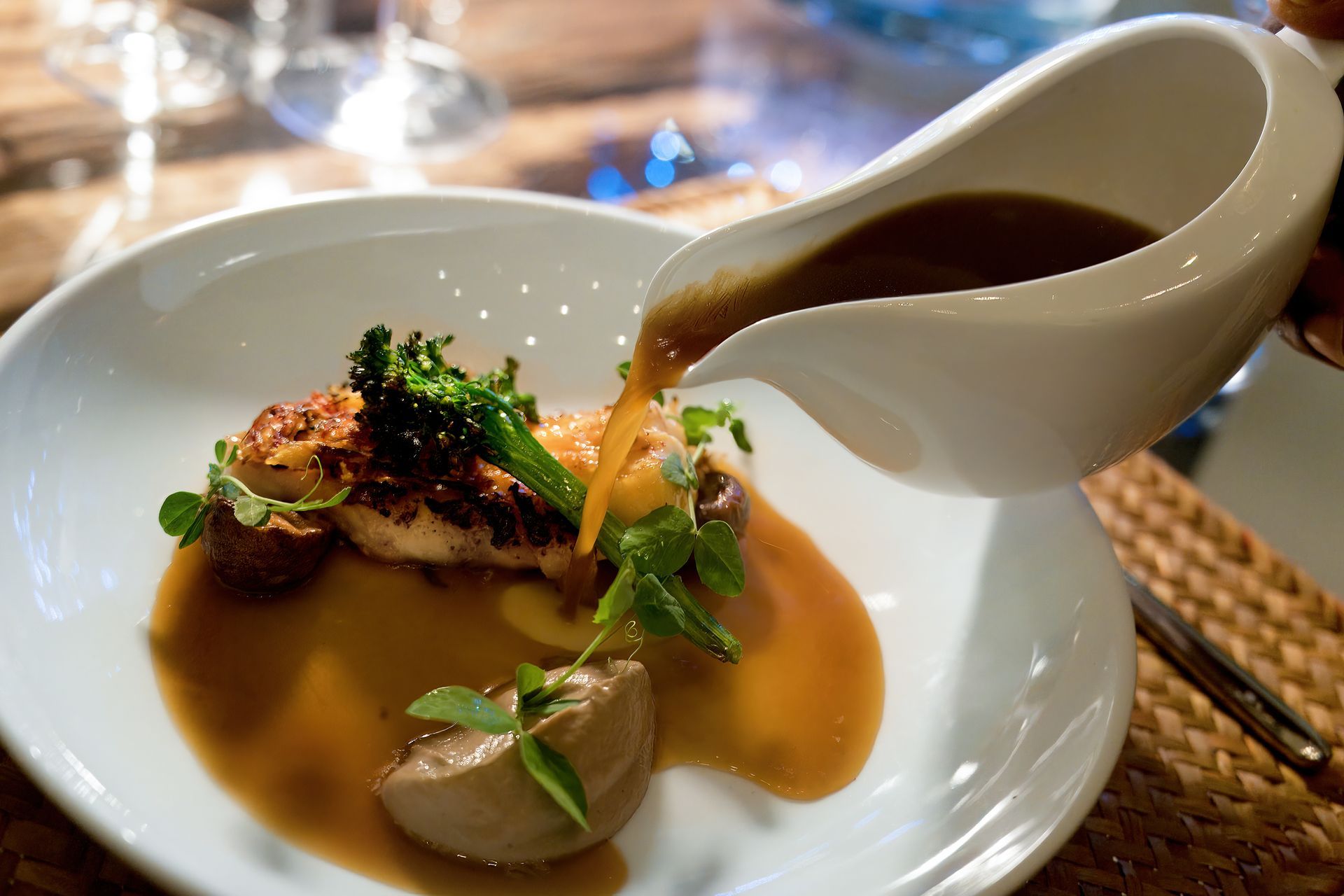 A person pouring sauce on a plate of food