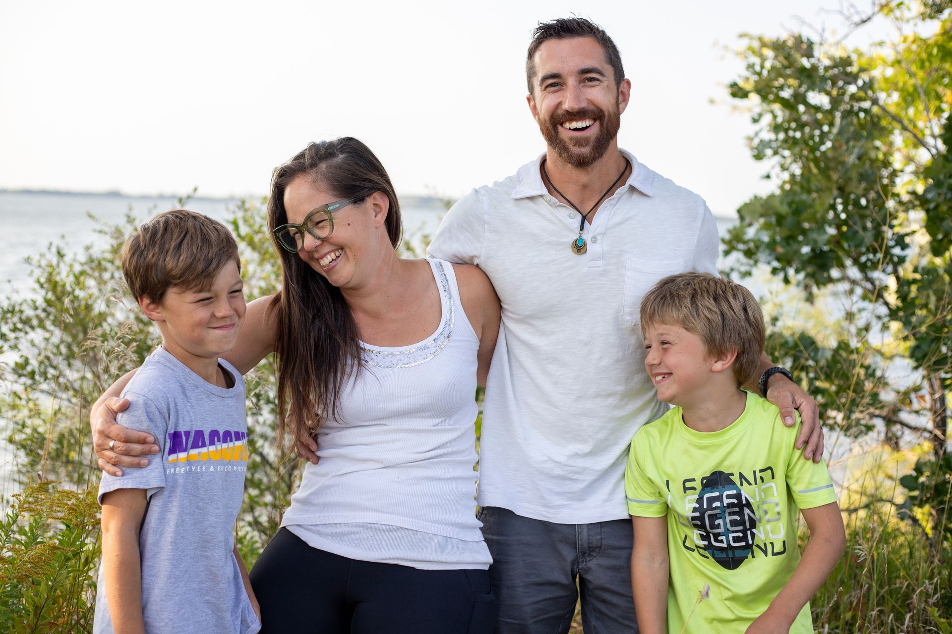 A family is posing for a picture in front of a body of water.