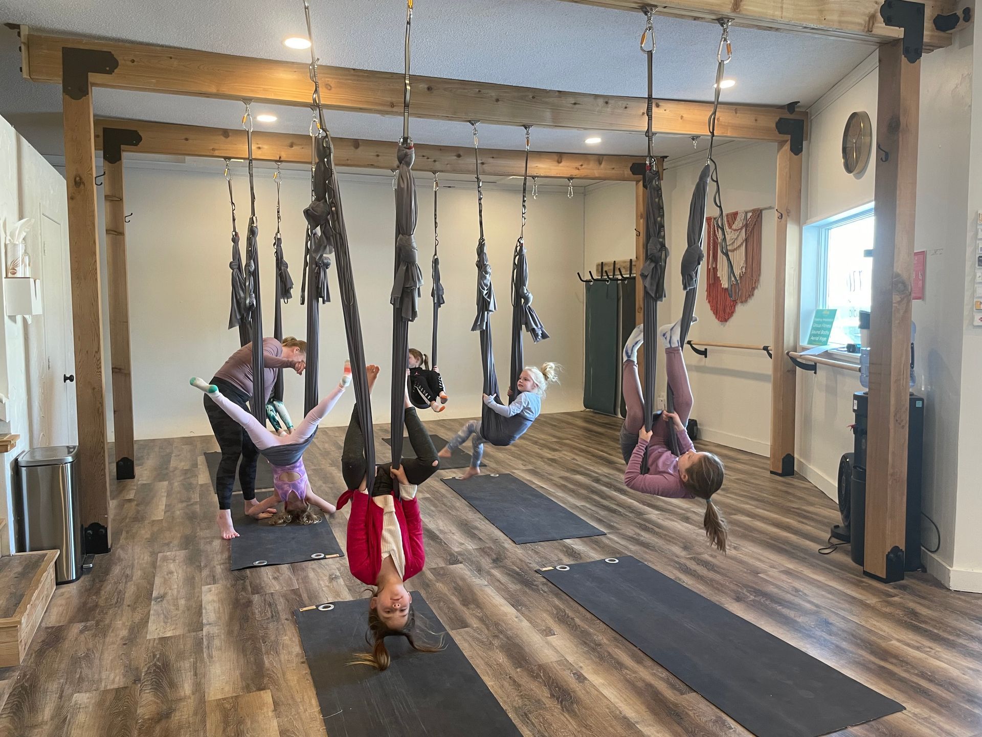 A group of people are doing aerial yoga in a gym.