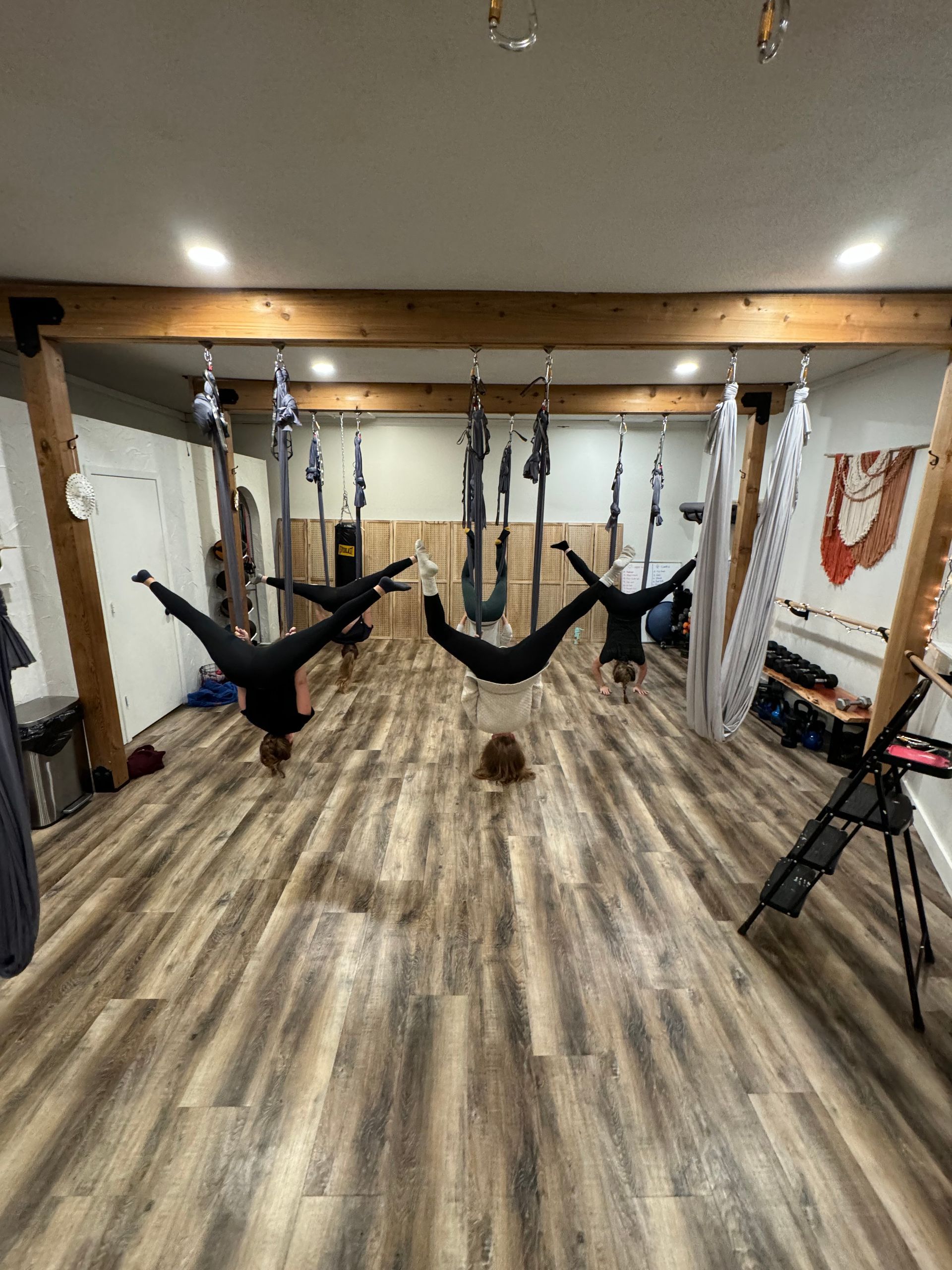 A group of people are doing aerial yoga in a gym.