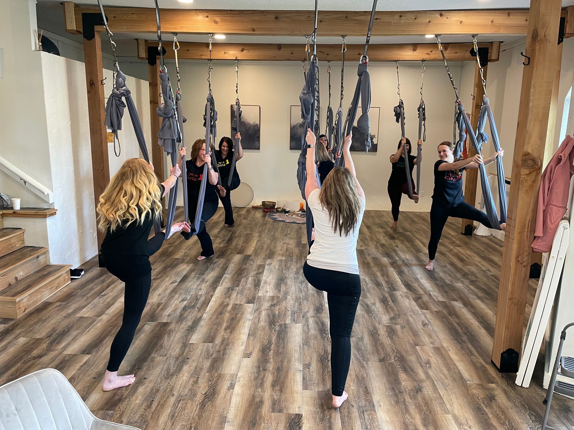 A group of people are doing aerial yoga in a room.