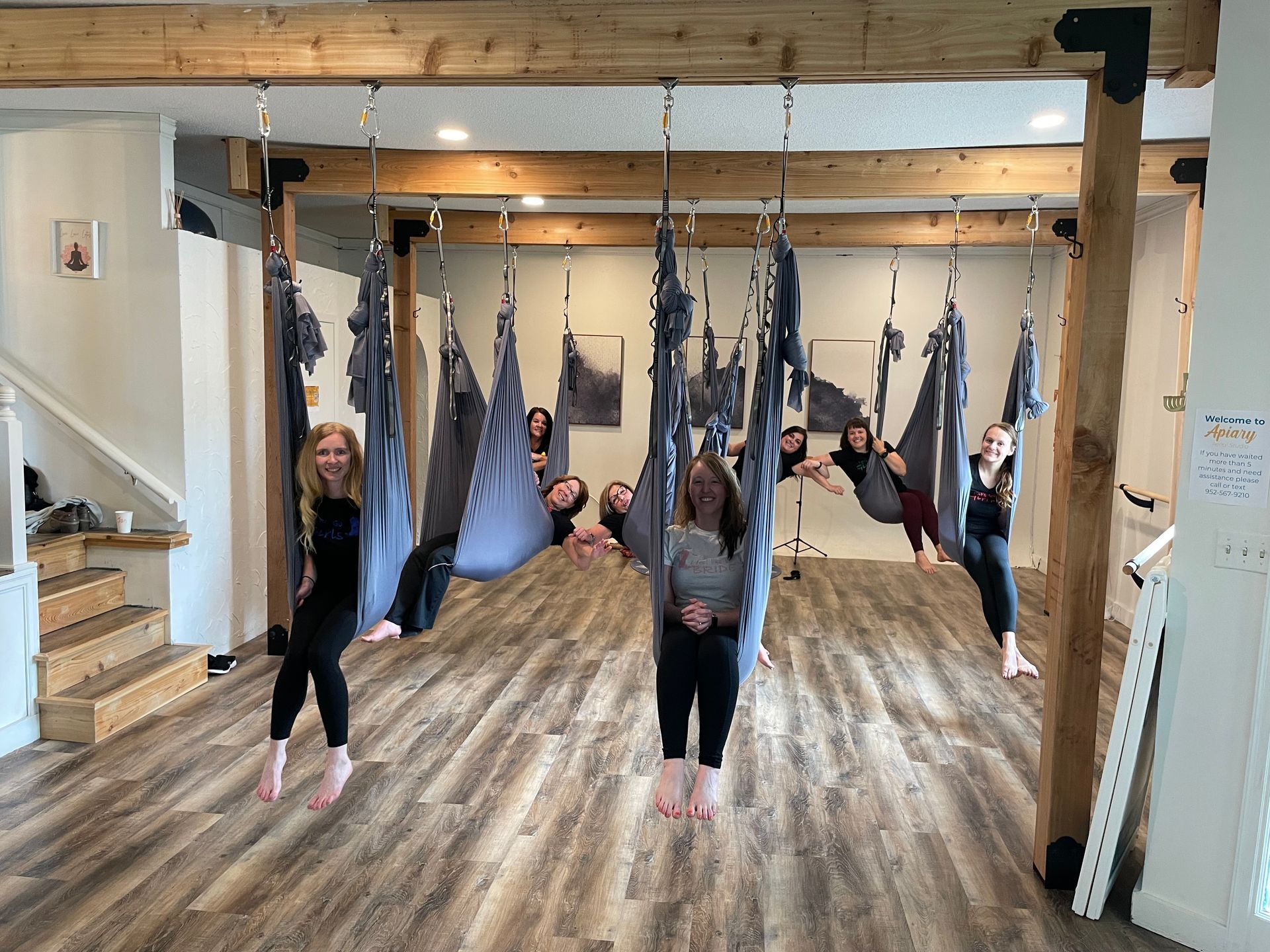 A group of people are hanging from hammocks in a room.