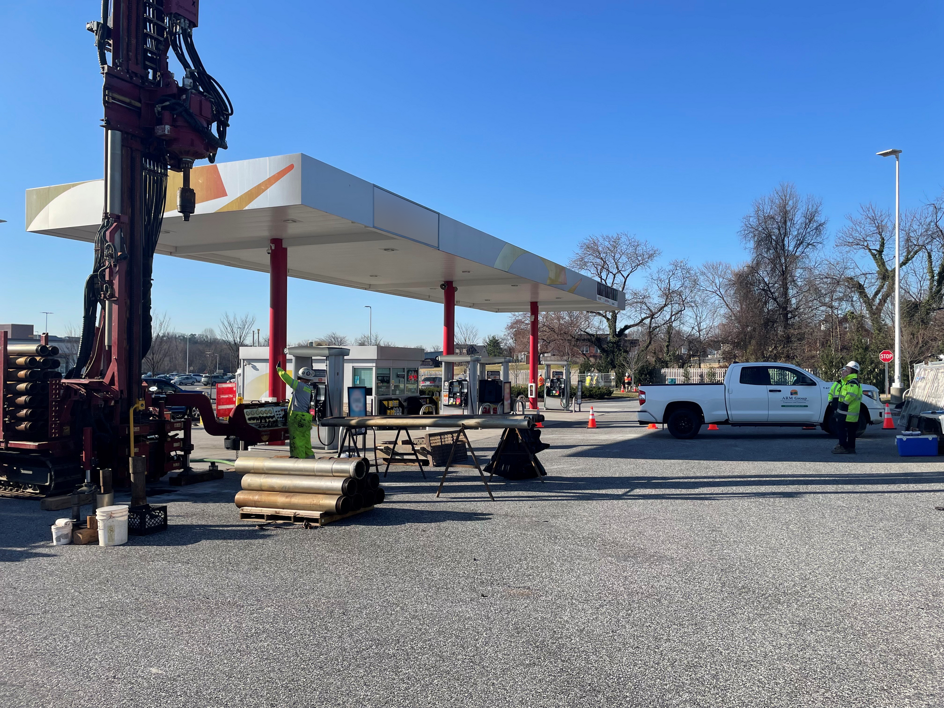 Field crew conducting vapor intrusion investigation and sonic drilling operations at an active fuel station site. Equipment and safety perimeter are in place.