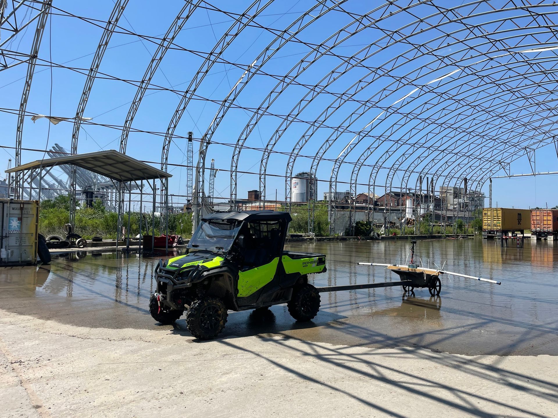 Side by side pulling geophysical survey equipment through wet abandoned hoop house