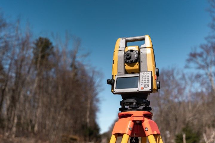 Total station mounted on tripod in a wooded area
